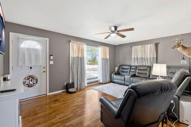 living room featuring baseboards, ceiling fan, visible vents, and wood finished floors