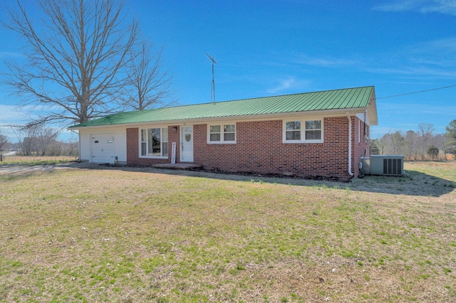 view of front of house with brick siding, an attached garage, central AC, metal roof, and a front lawn