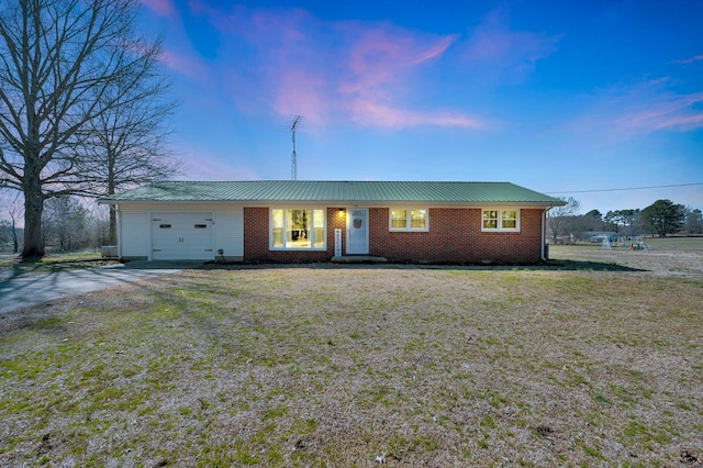 single story home featuring a garage, driveway, brick siding, and a yard