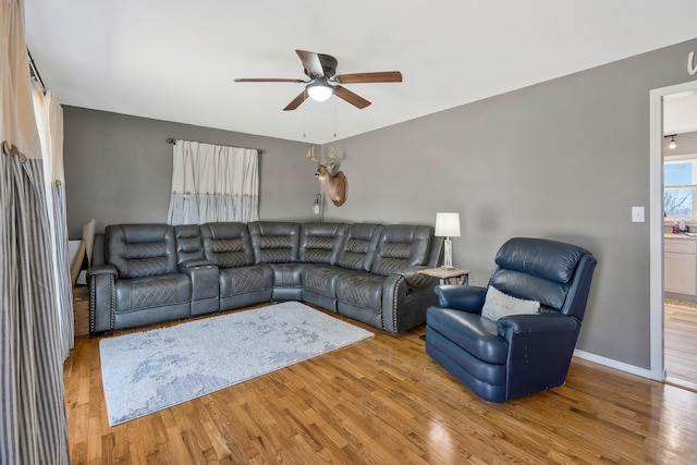 living area featuring ceiling fan, baseboards, and wood finished floors