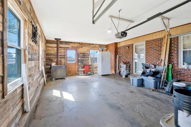 garage with a garage door opener, freestanding refrigerator, and wood walls