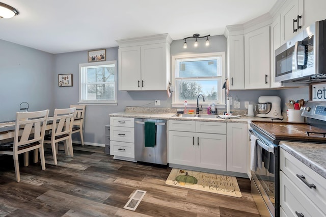 kitchen with white cabinets, stainless steel appliances, a sink, and light countertops