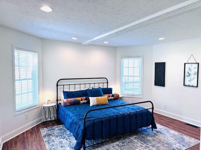 bedroom featuring dark hardwood / wood-style flooring, a textured ceiling, and multiple windows