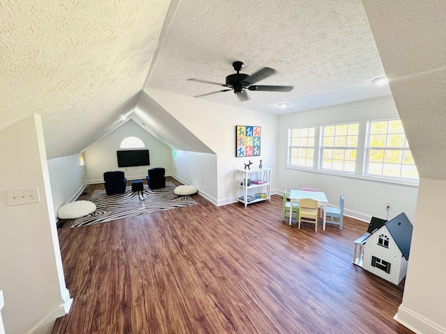 playroom featuring a textured ceiling, ceiling fan, dark wood-type flooring, and lofted ceiling