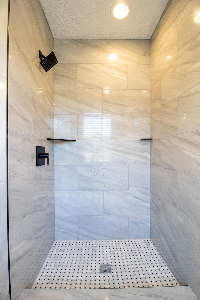 bathroom featuring a tile shower and a textured ceiling