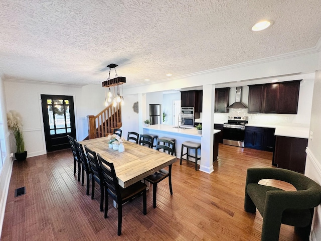 dining room with crown molding, sink, light hardwood / wood-style floors, and a textured ceiling