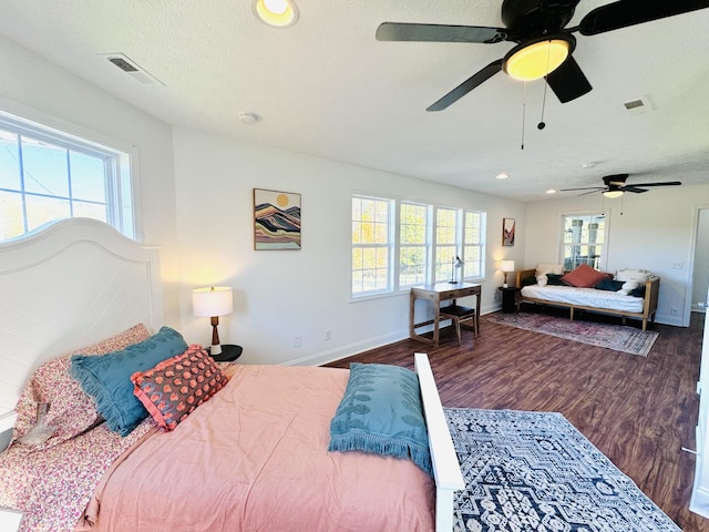 bedroom with a textured ceiling, ceiling fan, and dark hardwood / wood-style floors