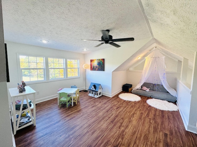 recreation room with lofted ceiling, a textured ceiling, ceiling fan, and dark wood-type flooring