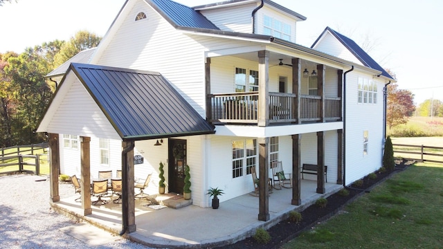 rear view of property featuring a patio area, ceiling fan, and a balcony