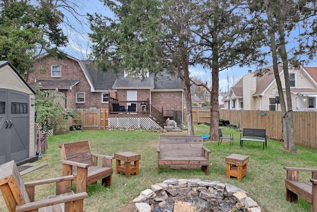 view of yard featuring an outdoor fire pit, a storage shed, and a wooden deck