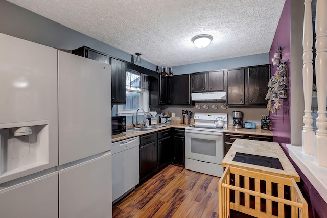 kitchen with a textured ceiling, white appliances, dark brown cabinetry, dark wood-type flooring, and sink