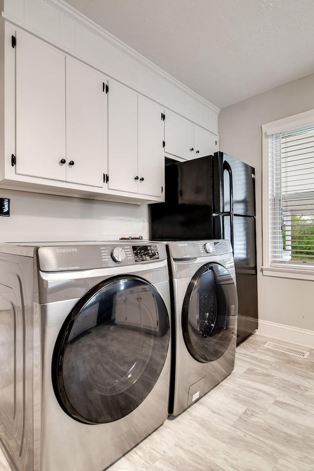 washroom with washer and dryer, light hardwood / wood-style floors, and cabinets