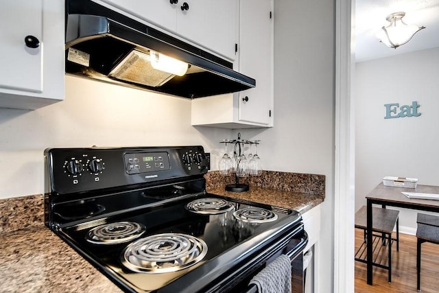 kitchen featuring white cabinets, dark stone countertops, hardwood / wood-style floors, and black electric range