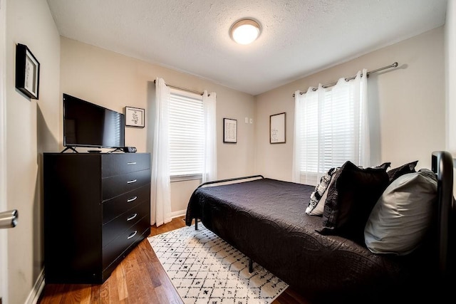 bedroom featuring hardwood / wood-style flooring, a textured ceiling, and multiple windows