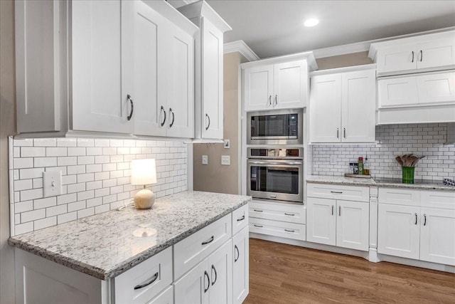 kitchen with tasteful backsplash, built in microwave, white cabinetry, and stainless steel oven