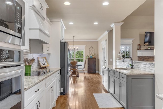 kitchen featuring white cabinets, appliances with stainless steel finishes, an inviting chandelier, and sink