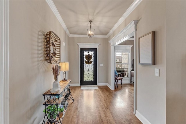 entryway with wood-type flooring, an inviting chandelier, and ornamental molding