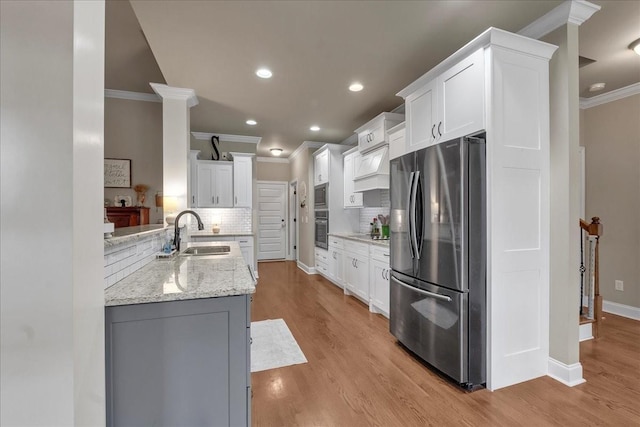 kitchen with kitchen peninsula, tasteful backsplash, stainless steel appliances, sink, and white cabinetry