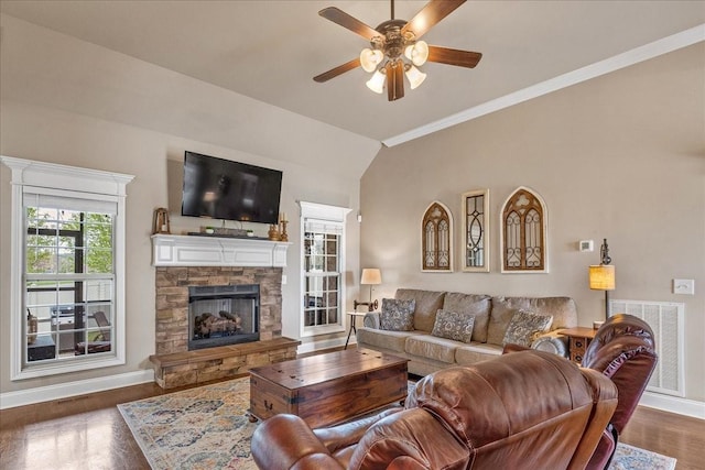 living room featuring ceiling fan, a stone fireplace, dark hardwood / wood-style floors, crown molding, and lofted ceiling