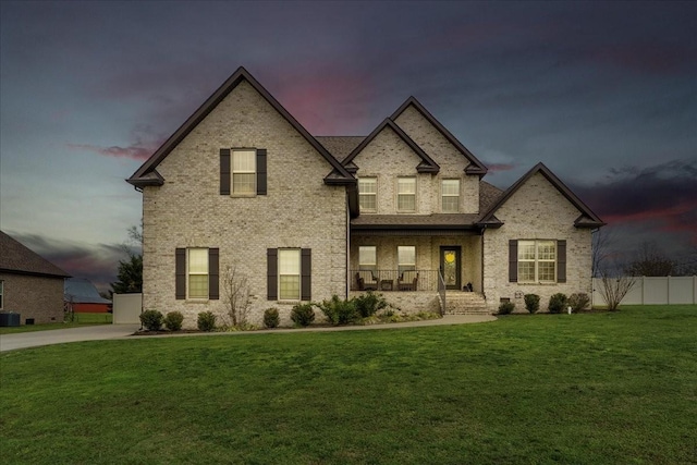 french country home featuring a lawn, cooling unit, and covered porch