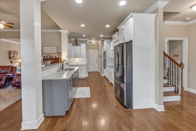 kitchen with decorative backsplash, appliances with stainless steel finishes, ceiling fan, sink, and white cabinetry