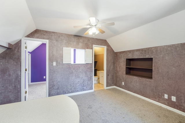 additional living space with vaulted ceiling, carpet flooring, ceiling fan, and built in shelves