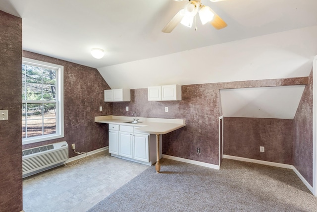 kitchen with vaulted ceiling, sink, white cabinets, ceiling fan, and a wall unit AC