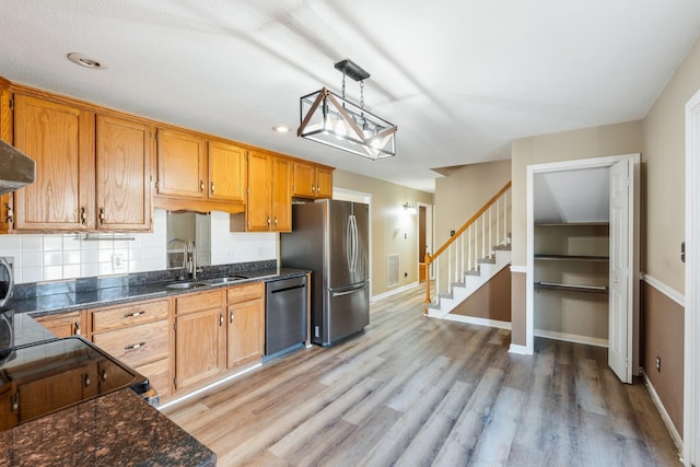 kitchen featuring decorative light fixtures, tasteful backsplash, sink, light hardwood / wood-style floors, and stainless steel appliances