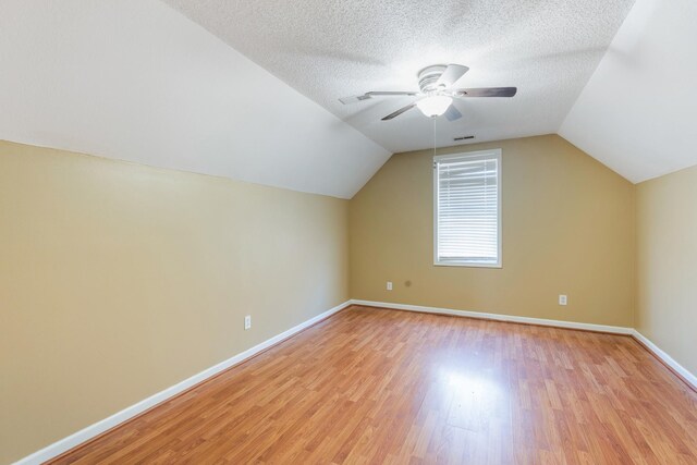 additional living space featuring vaulted ceiling, ceiling fan, a textured ceiling, and light hardwood / wood-style floors