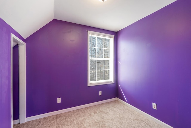 carpeted spare room with lofted ceiling