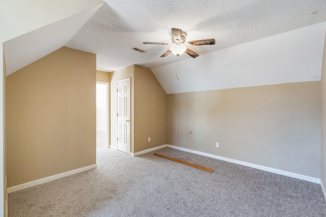 additional living space with ceiling fan, lofted ceiling, carpet, and a textured ceiling