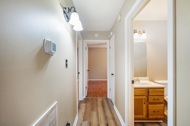 corridor featuring sink and light wood-type flooring