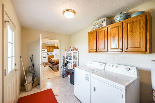 washroom with cabinets, a textured ceiling, and independent washer and dryer