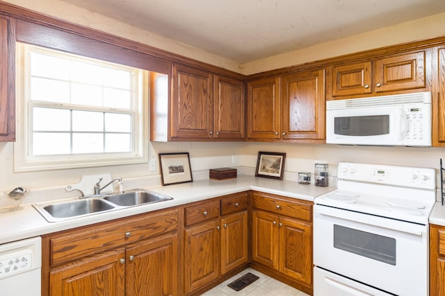 kitchen featuring light tile patterned flooring, white appliances, and sink