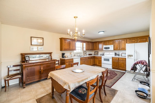 kitchen with sink, pendant lighting, white appliances, and an inviting chandelier