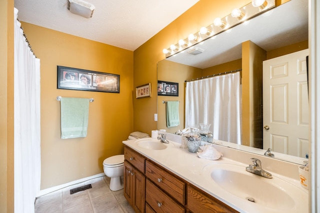 bathroom with tile patterned flooring, vanity, toilet, and a textured ceiling