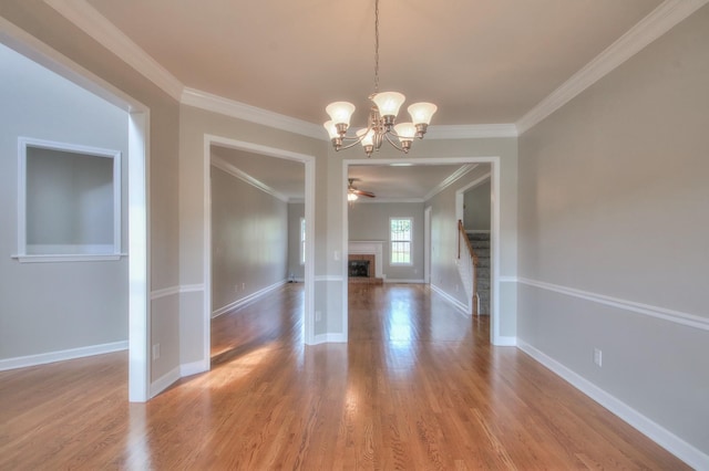 unfurnished dining area featuring hardwood / wood-style floors, ceiling fan with notable chandelier, and ornamental molding