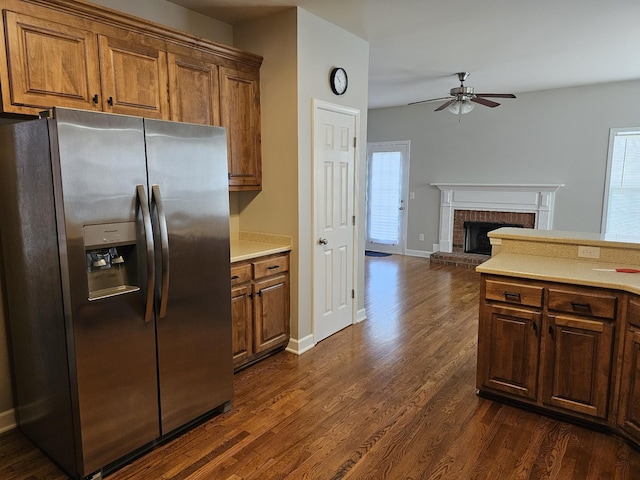 kitchen featuring stainless steel refrigerator with ice dispenser, dark hardwood / wood-style flooring, a brick fireplace, and ceiling fan