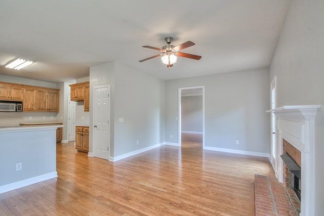 unfurnished living room with ceiling fan, light hardwood / wood-style floors, and a fireplace