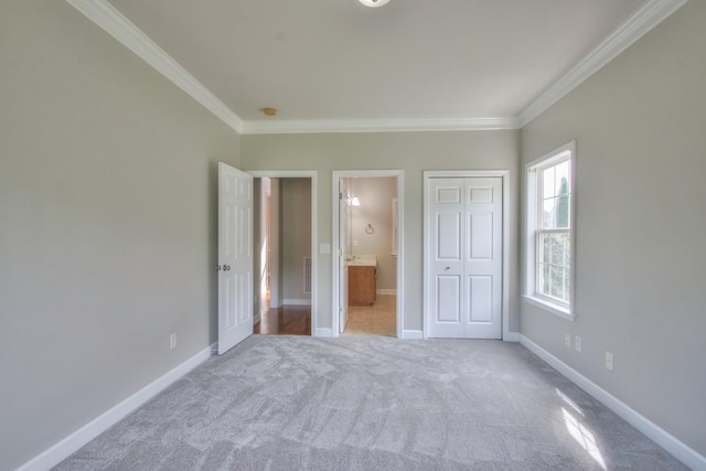 unfurnished bedroom with light colored carpet, ensuite bath, a closet, and crown molding