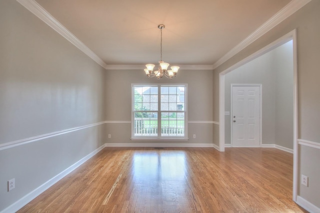 spare room with light wood-type flooring, ornamental molding, and a chandelier