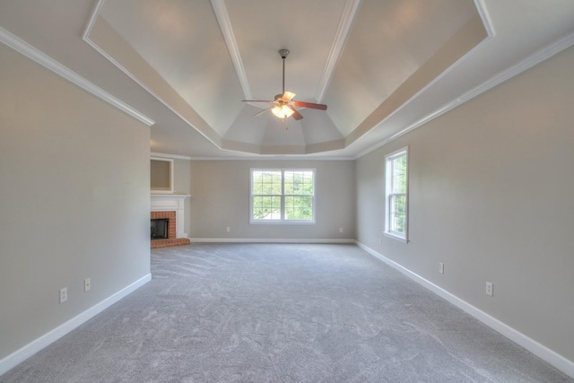 unfurnished living room featuring ceiling fan, a raised ceiling, ornamental molding, and a fireplace