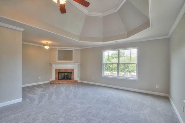 unfurnished living room featuring ornamental molding, a fireplace, light carpet, and a tray ceiling