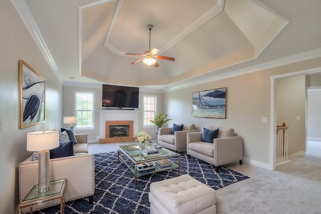 carpeted living room featuring ceiling fan, crown molding, a fireplace, and a tray ceiling