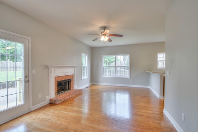 unfurnished living room featuring a fireplace, light hardwood / wood-style flooring, ceiling fan, and a healthy amount of sunlight