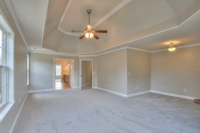 empty room featuring a tray ceiling, ceiling fan, crown molding, and light carpet