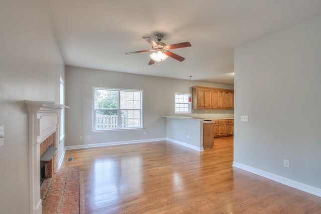 unfurnished living room with a fireplace, light hardwood / wood-style flooring, and ceiling fan