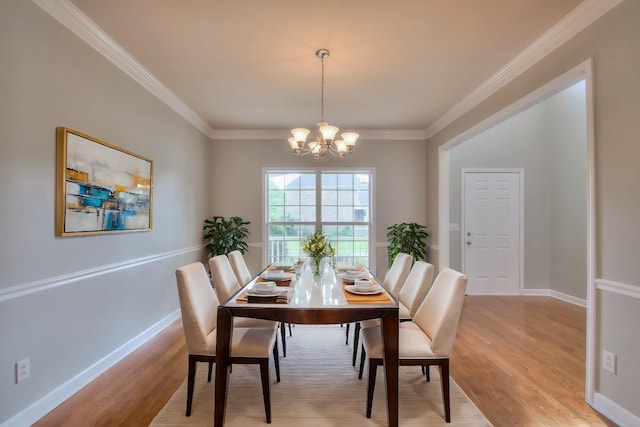 dining area with crown molding, light wood-type flooring, and an inviting chandelier