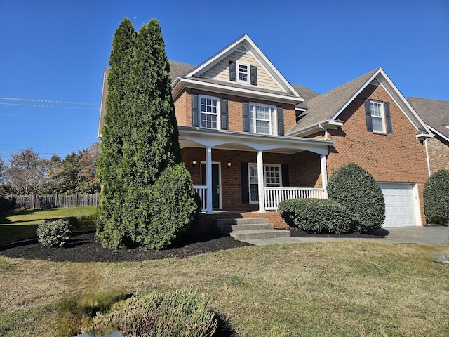 view of front of property featuring covered porch, a garage, and a front lawn