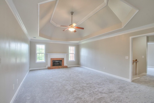 unfurnished living room with ceiling fan, ornamental molding, a fireplace, and a tray ceiling